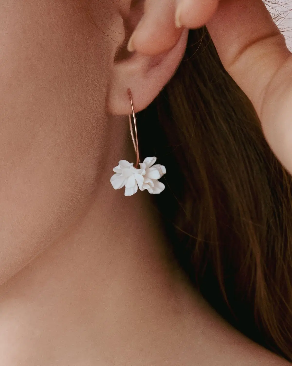 Nahaufnahme einer Braut im Profil mit den hängenden Valeria Ohrringen aus 925 Sterling Silber 18k rosévergoldet. Die weißen Brautohrringe aus der Sternenauge Manufaktur kommen vor den braunen Haaren besonders edel zur Geltung.