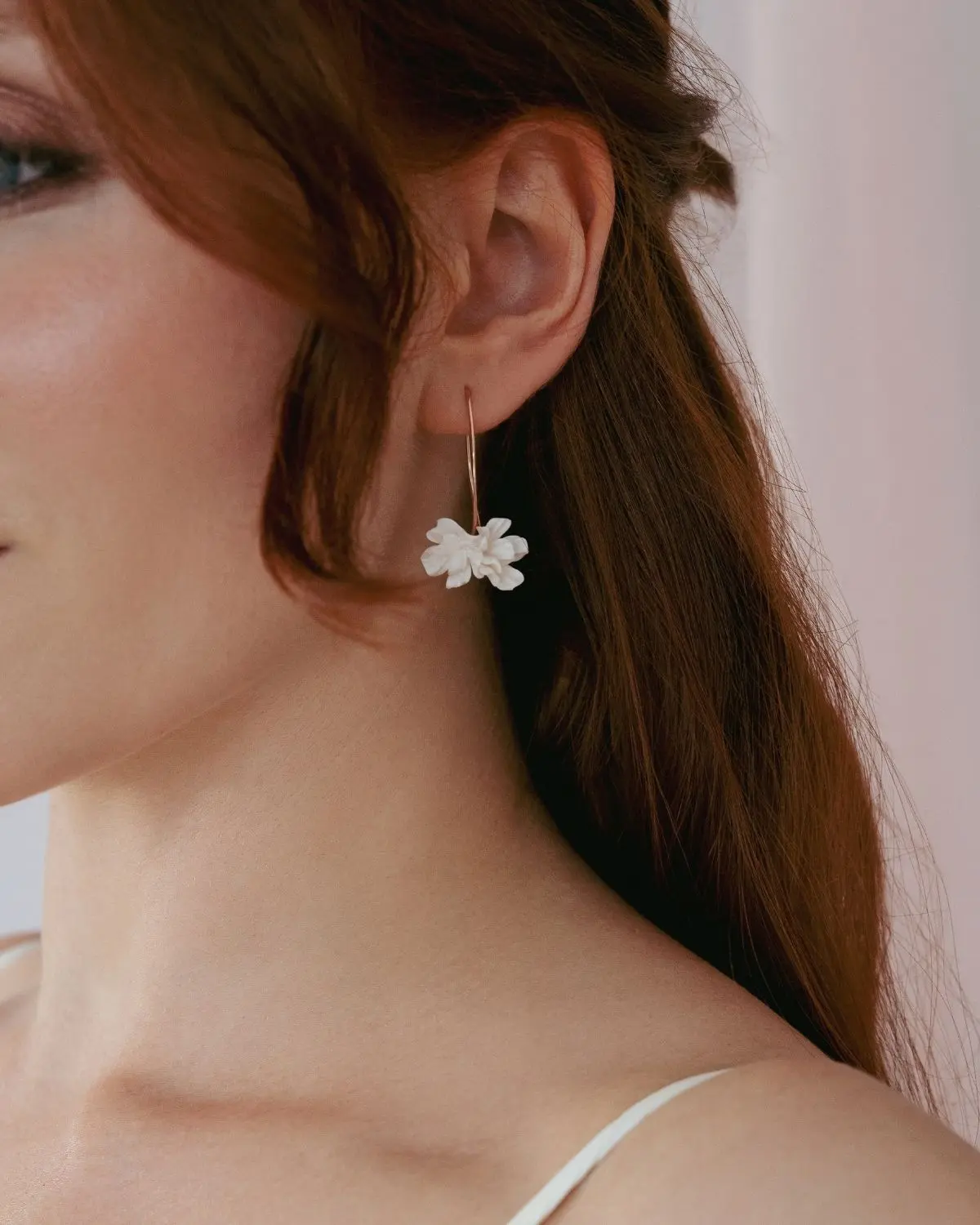 Nahaufnahme einer rothaarigen Braut von der Seite im Profil. Sie trägt die Valeria Ohrhänger von Sternenauge mit filigranen, handgeformten weißen Blüten, die elegant vor ihren braunen Haaren hängen.