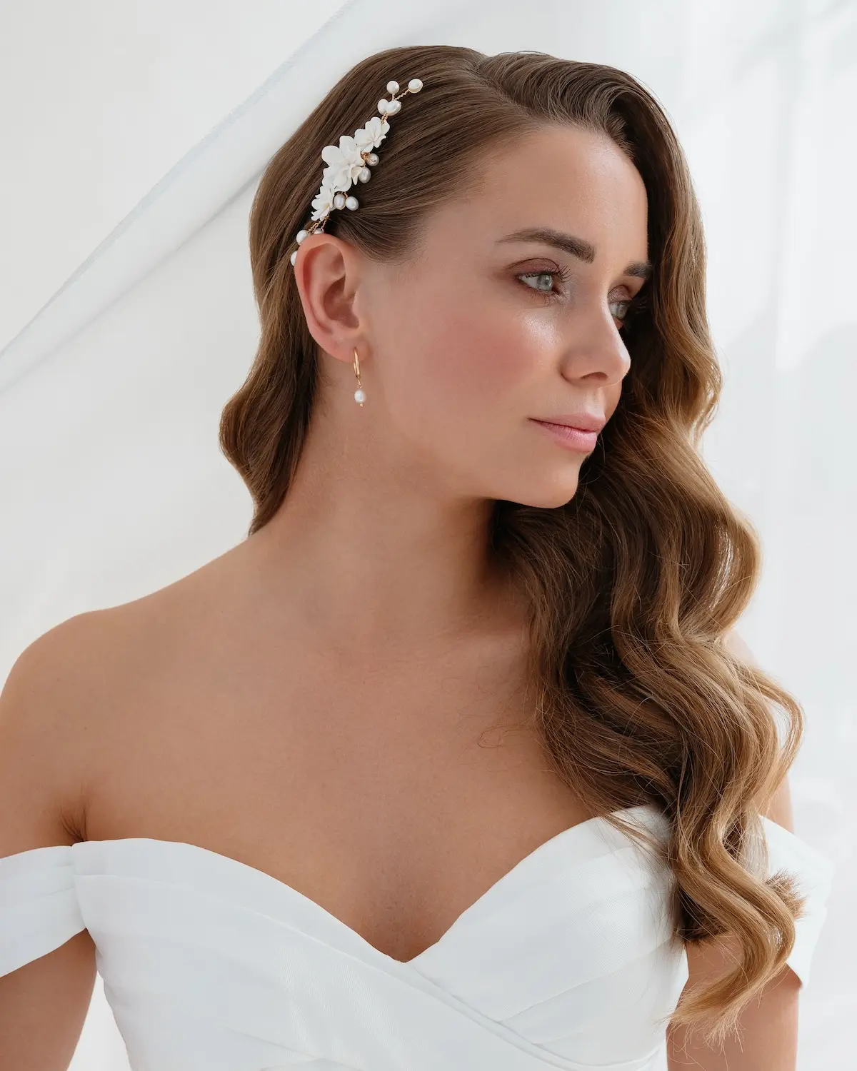 Braut im eleganten Brautkleid hat eine moderne Brautfrisur mit Wasserwelle und dazu Haarkamm MIEVAL mit Blumen und echten Süßwasser-Zuchtperlen von Sternenauge im Haar