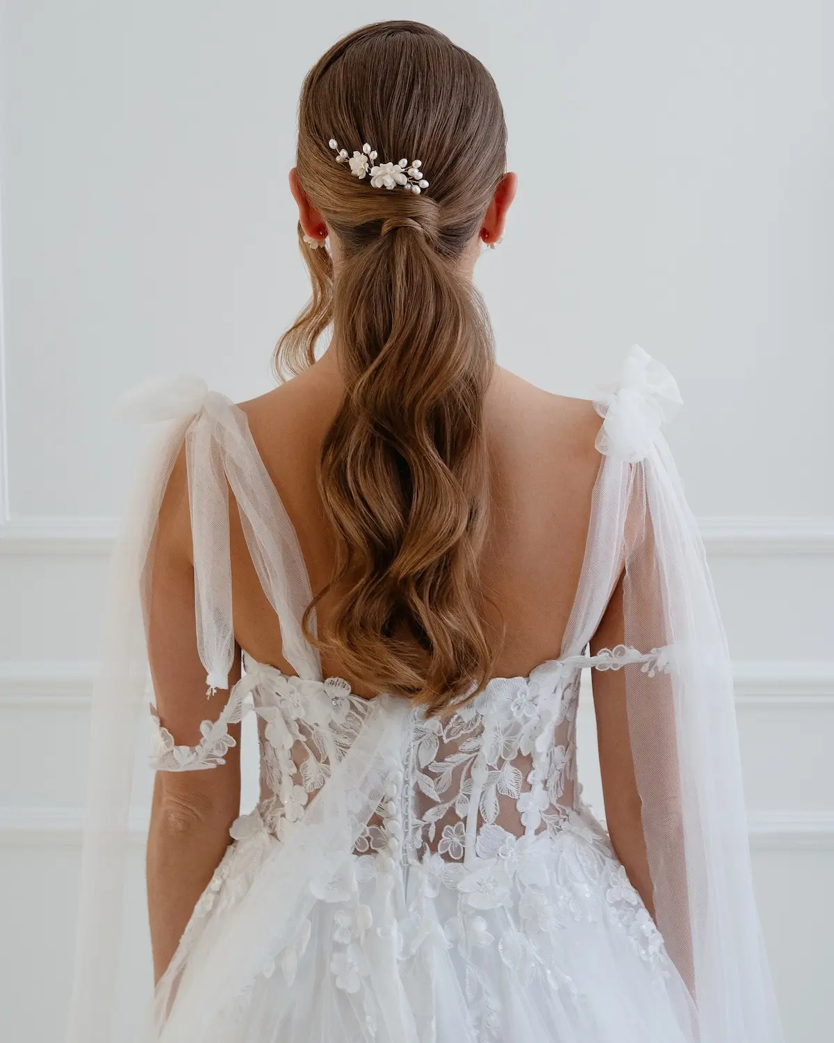 Braut mit romantischem Brautkleid trägt Blumen Haarnadel MIEVAL mit echten Süßwasser-Zuchtperlen von Sternenauge zum modernen Ponytail