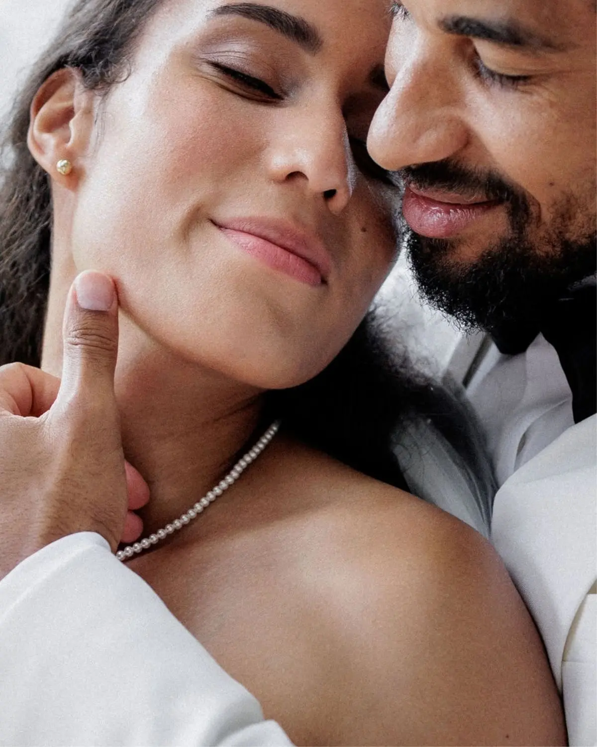 Zärtlicher Moment eines Hochzeitspaares, bei dem die Braut die klassische Perlenkette Annouk mit Muschelkernperlen trägt