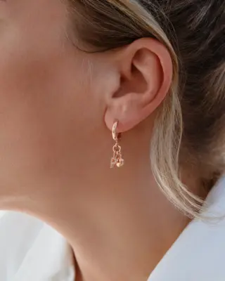 Eine Frau trägt die Bobby Creolen von Sternenauge mit Herz-Anhänger und glitzerndem Zirkonia-Wunschbuchstaben als eleganten Ohrschmuck aus 925 Sterling Silber